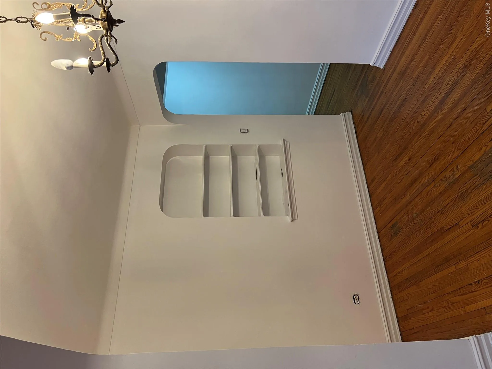 Spare room featuring dark hardwood / wood-style flooring, built in features, and a notable chandelier Spare room featuring dark hardwood / wood-style flooring, built in features, and a notable chandelier