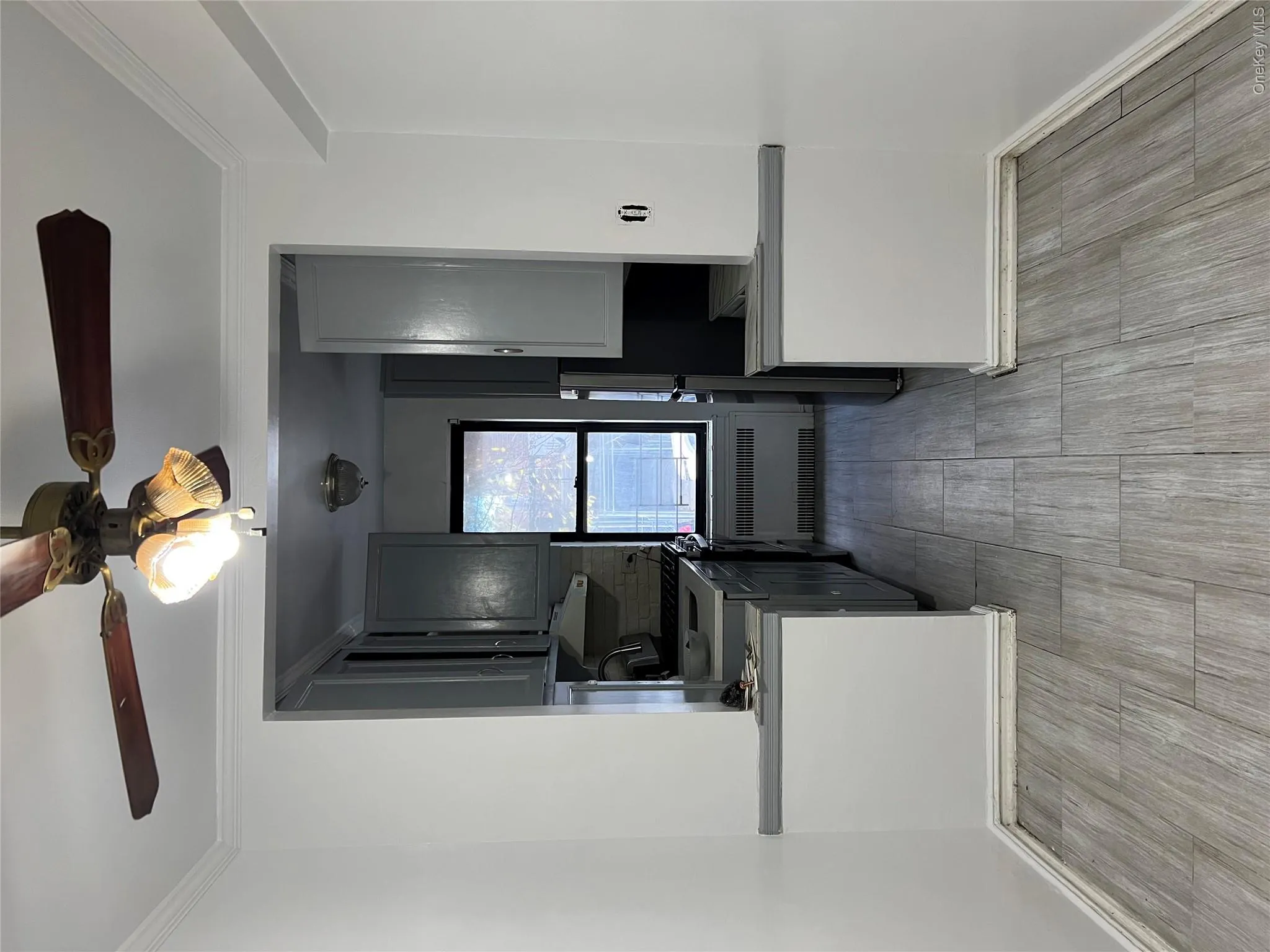 Kitchen with ornamental molding, light hardwood / wood-style flooring, radiator, and gray cabinetry Kitchen with ornamental molding, light hardwood / wood-style flooring, radiator, and gray cabinetry