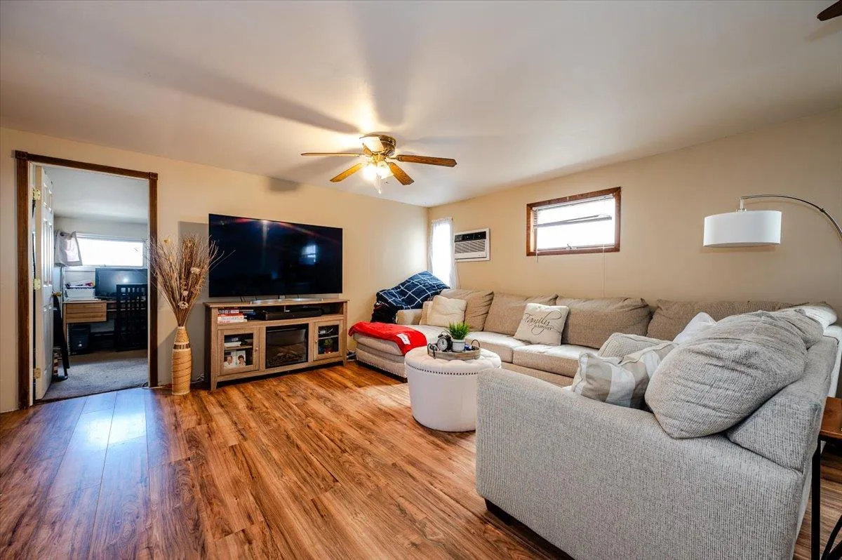 Living room with hardwood / wood-style flooring, a wall mounted AC, and ceiling fan Living room with hardwood / wood-style flooring, a wall mounted AC, and ceiling fan