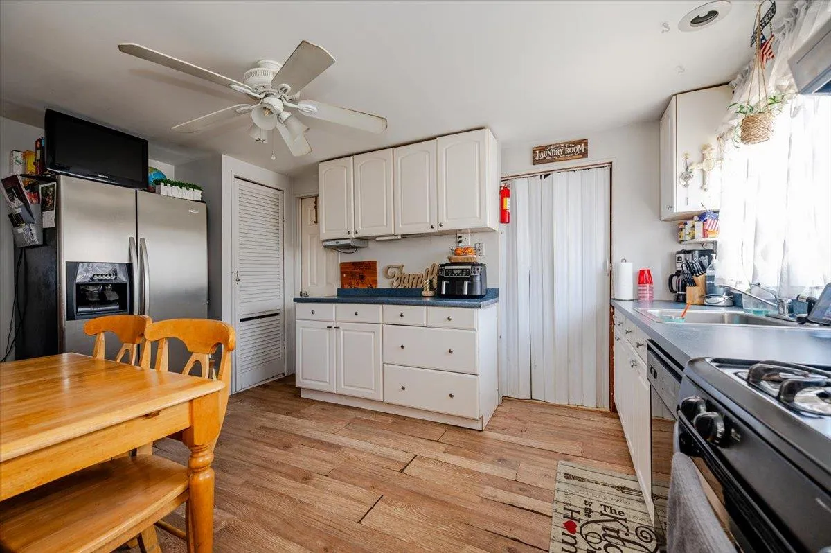 Kitchen with sink, light hardwood / wood-style flooring, stainless steel fridge with ice dispenser, ceiling fan, and white cabinetry Kitchen with sink, light hardwood / wood-style flooring, stainless steel fridge with ice dispenser, ceiling fan, and white cabinetry