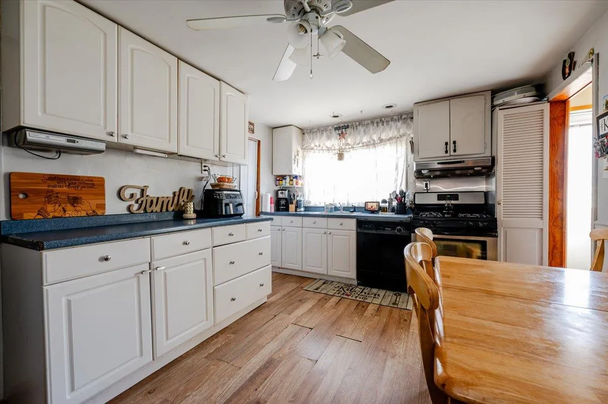 Kitchen featuring white cabinetry, stainless steel gas stove, a healthy amount of sunlight, and light wood-type flooring Kitchen featuring white cabinetry, stainless steel gas stove, a healthy amount of sunlight, and light wood-type flooring