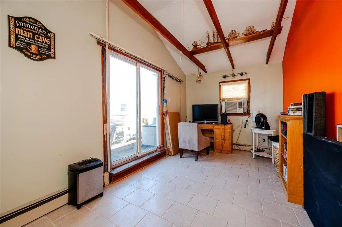 Tiled home office with lofted ceiling with beams, cooling unit, and a baseboard heating unit Tiled home office with lofted ceiling with beams, cooling unit, and a baseboard heating unit