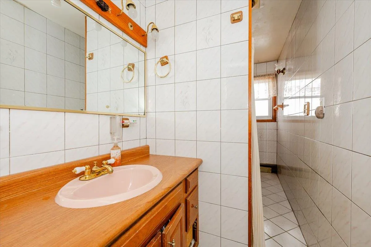 Bathroom featuring vanity, tasteful backsplash, and tile walls Bathroom featuring vanity, tasteful backsplash, and tile walls