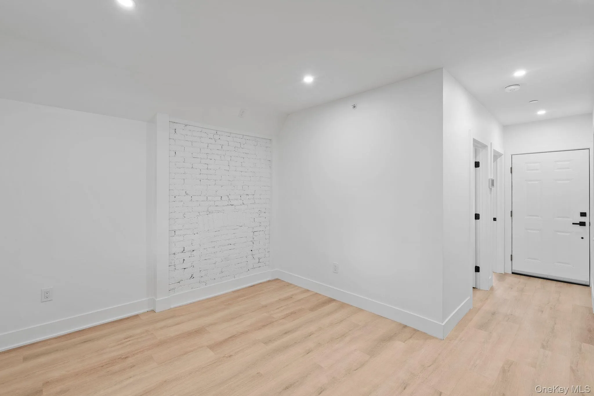 Empty room featuring light hardwood / wood-style flooring and brick wall Empty room featuring light hardwood / wood-style flooring and brick wall