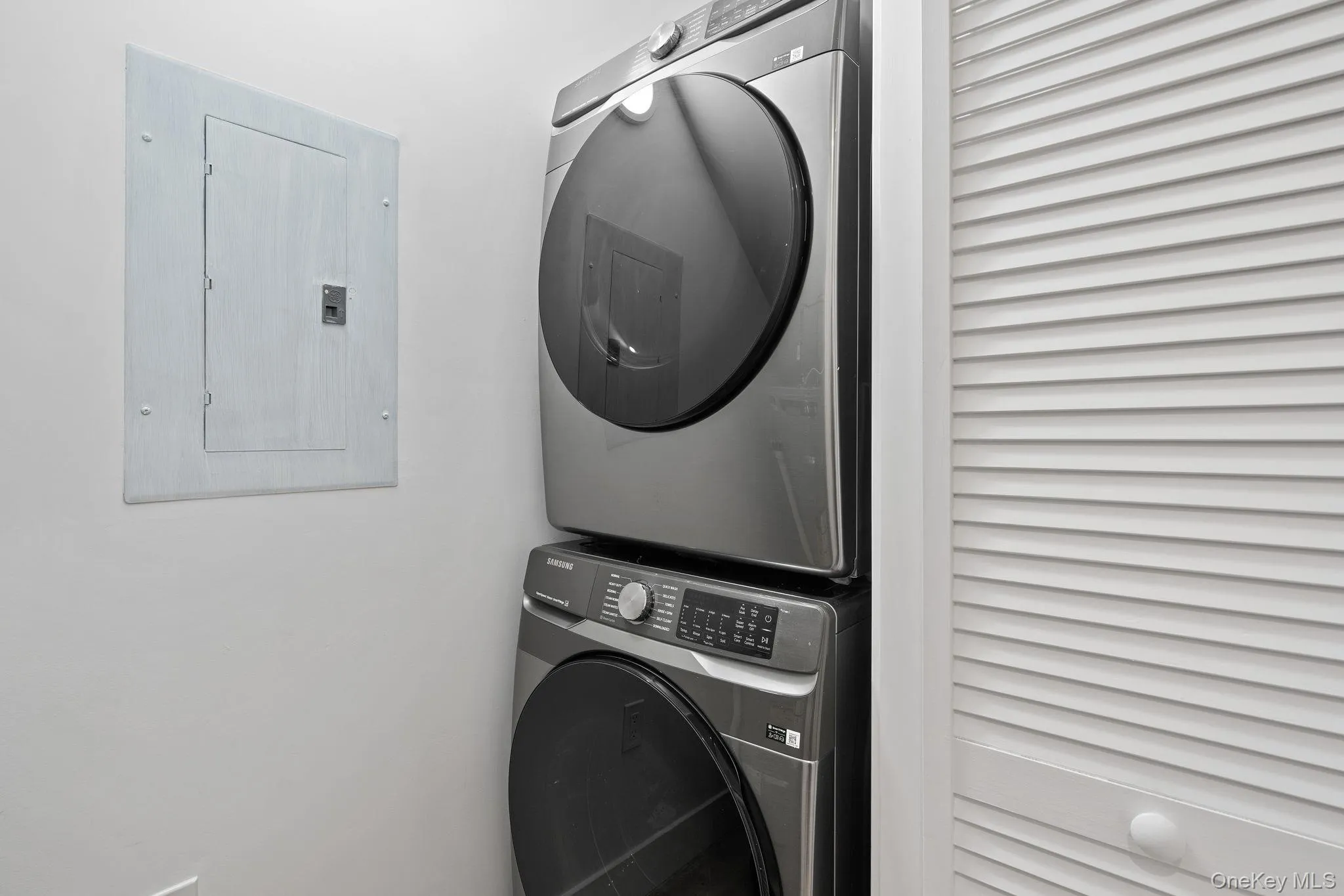 Clothes washing area featuring electric panel and stacked washer and clothes dryer Clothes washing area featuring electric panel and stacked washer and clothes dryer