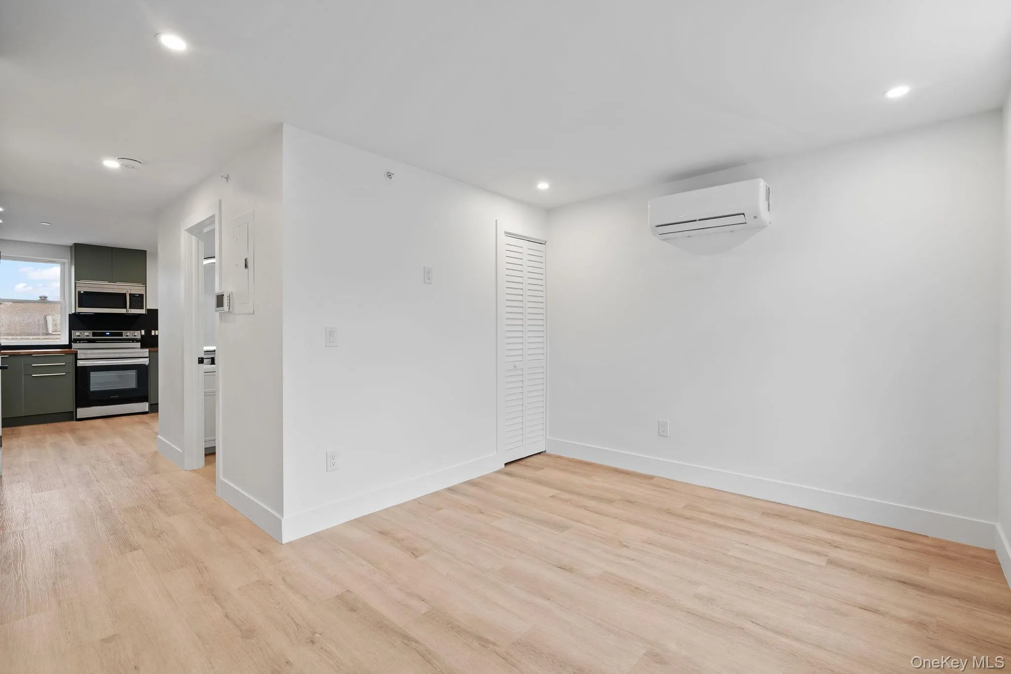 Spare room featuring a wall mounted air conditioner and light wood-type flooring Spare room featuring a wall mounted air conditioner and light wood-type flooring