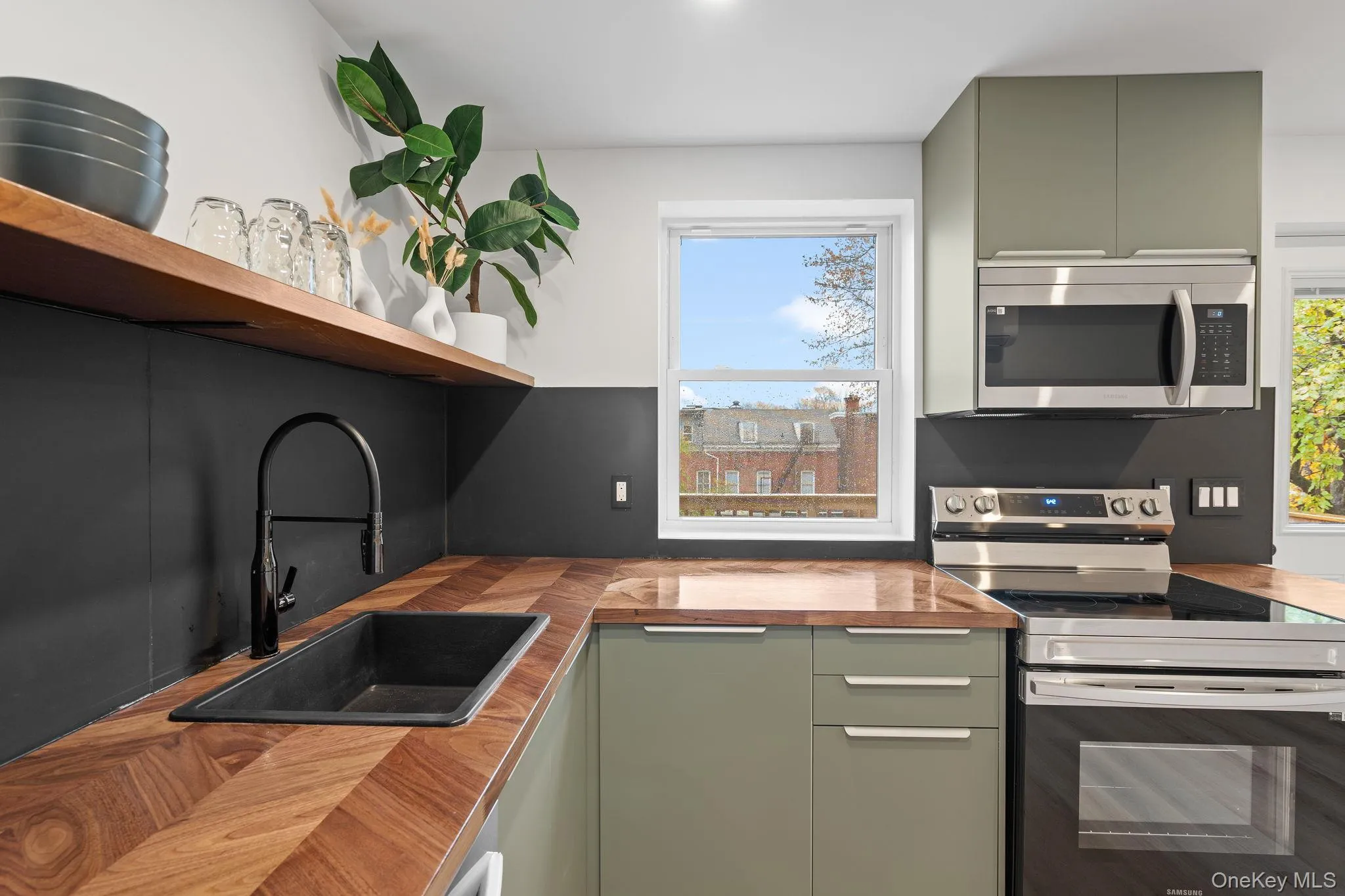 Kitchen featuring butcher block countertops, green cabinets, sink, and stainless steel appliances Kitchen featuring butcher block countertops, green cabinets, sink, and stainless steel appliances