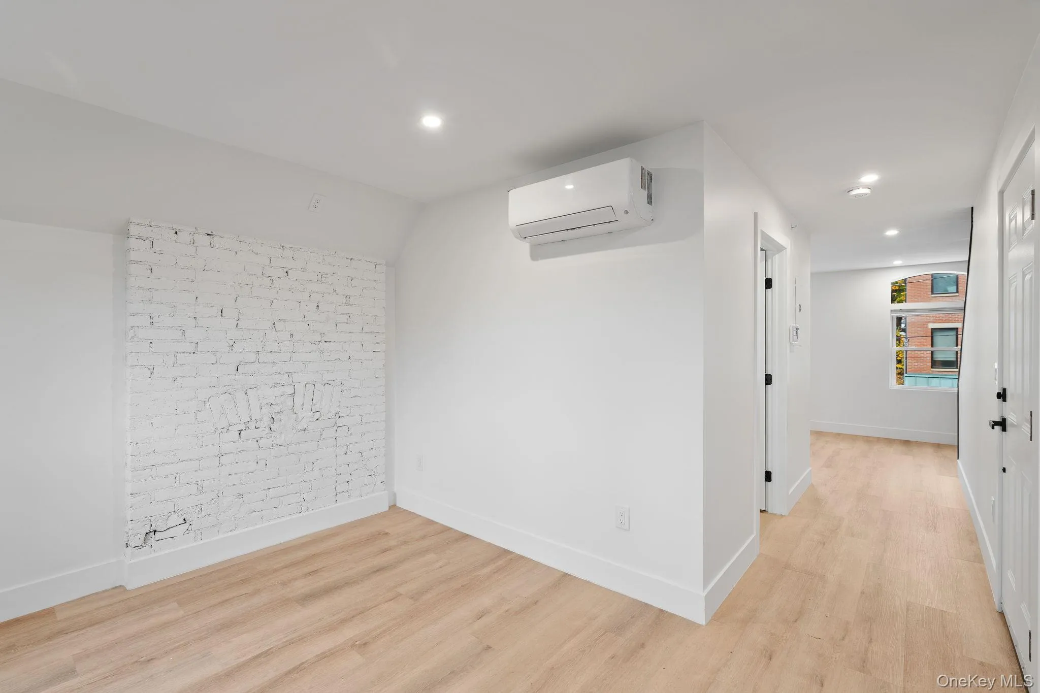 Unfurnished room with a wall mounted AC and light hardwood / wood-style floors Unfurnished room with a wall mounted AC and light hardwood / wood-style floors