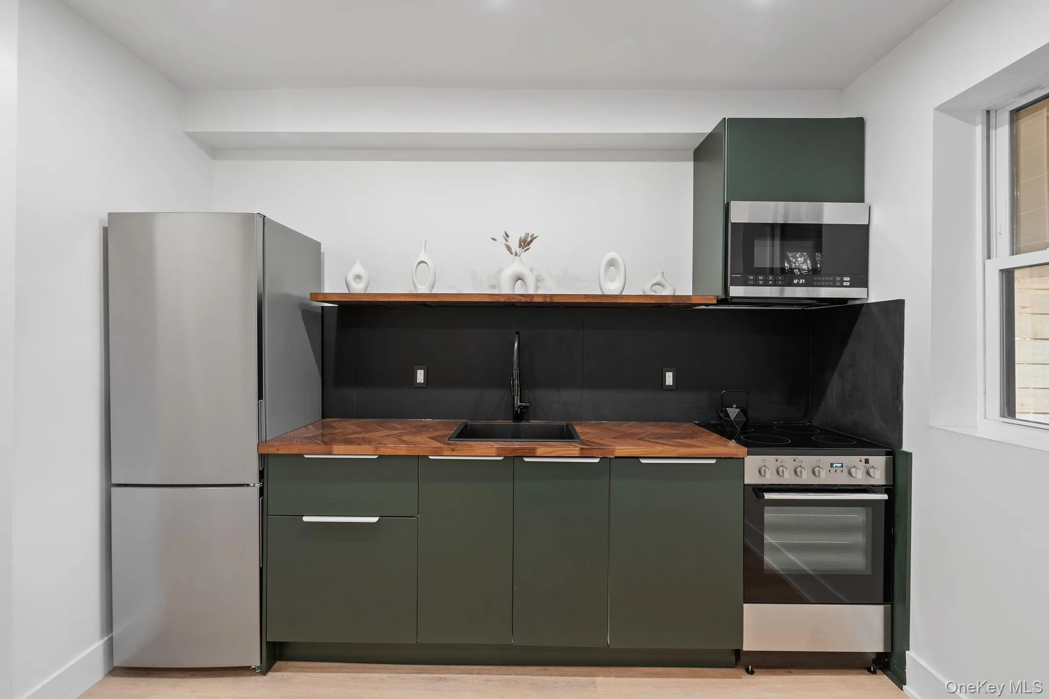 Kitchen featuring butcher block counters, sink, green cabinetry, and appliances with stainless steel finishes Kitchen featuring butcher block counters, sink, green cabinetry, and appliances with stainless steel finishes