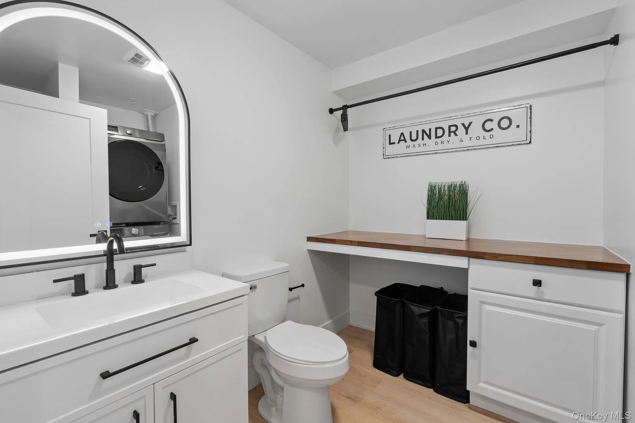 Bathroom featuring hardwood / wood-style floors, vanity, toilet, and stacked washer and dryer Bathroom featuring hardwood / wood-style floors, vanity, toilet, and stacked washer and dryer