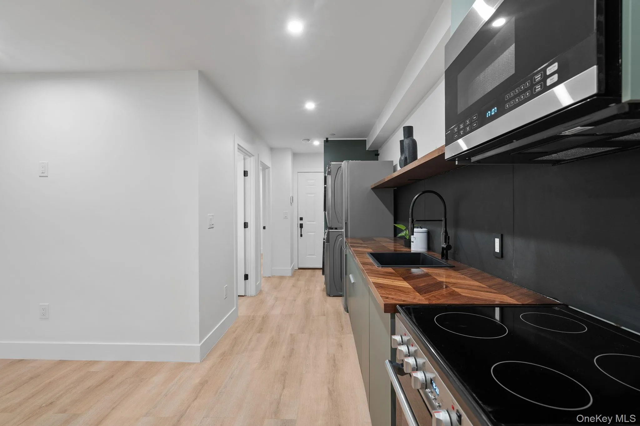 Kitchen with light hardwood / wood-style floors, sink, and appliances with stainless steel finishes Kitchen with light hardwood / wood-style floors, sink, and appliances with stainless steel finishes