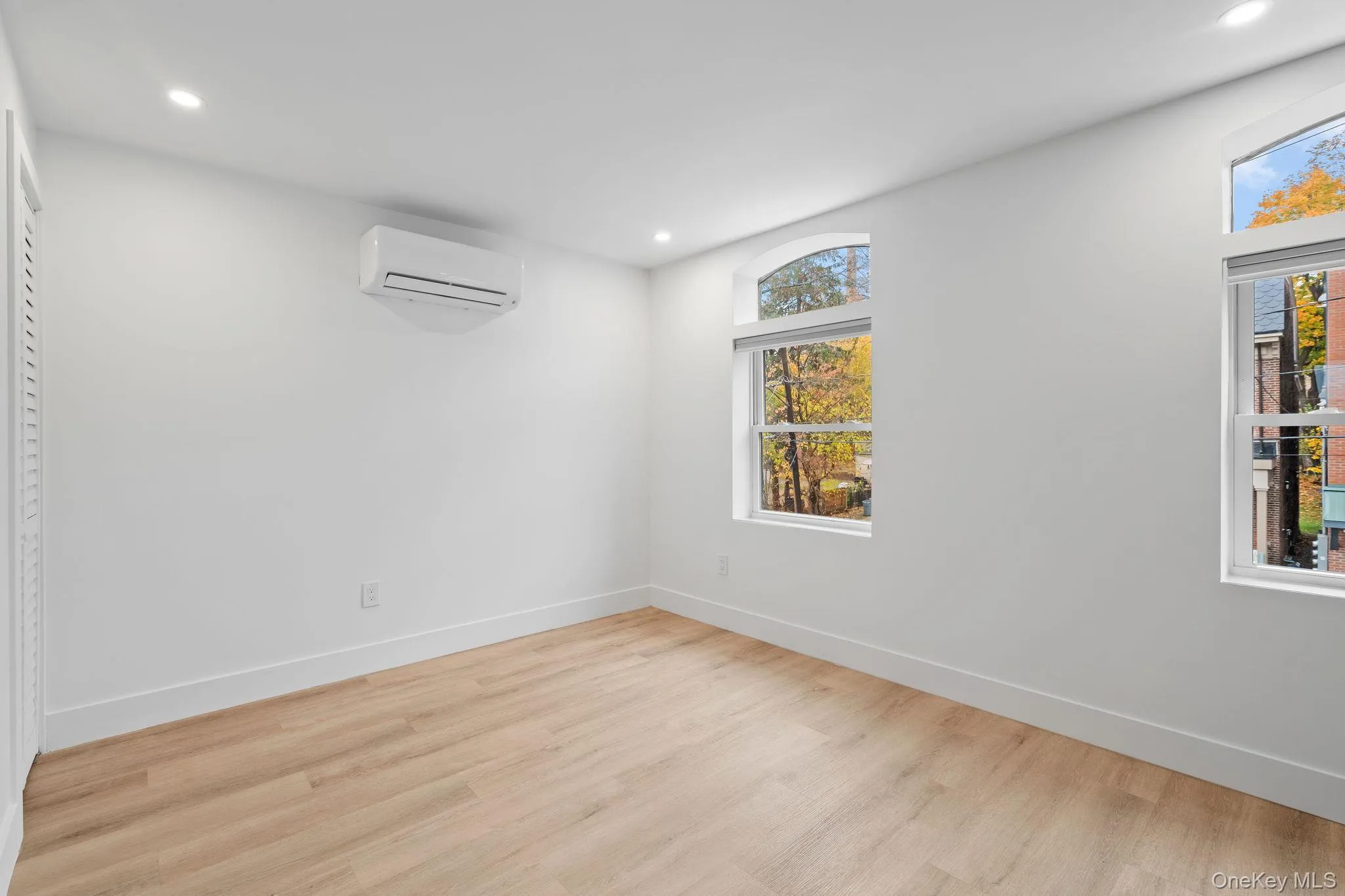 Unfurnished room with light hardwood / wood-style floors and an AC wall unit Unfurnished room with light hardwood / wood-style floors and an AC wall unit