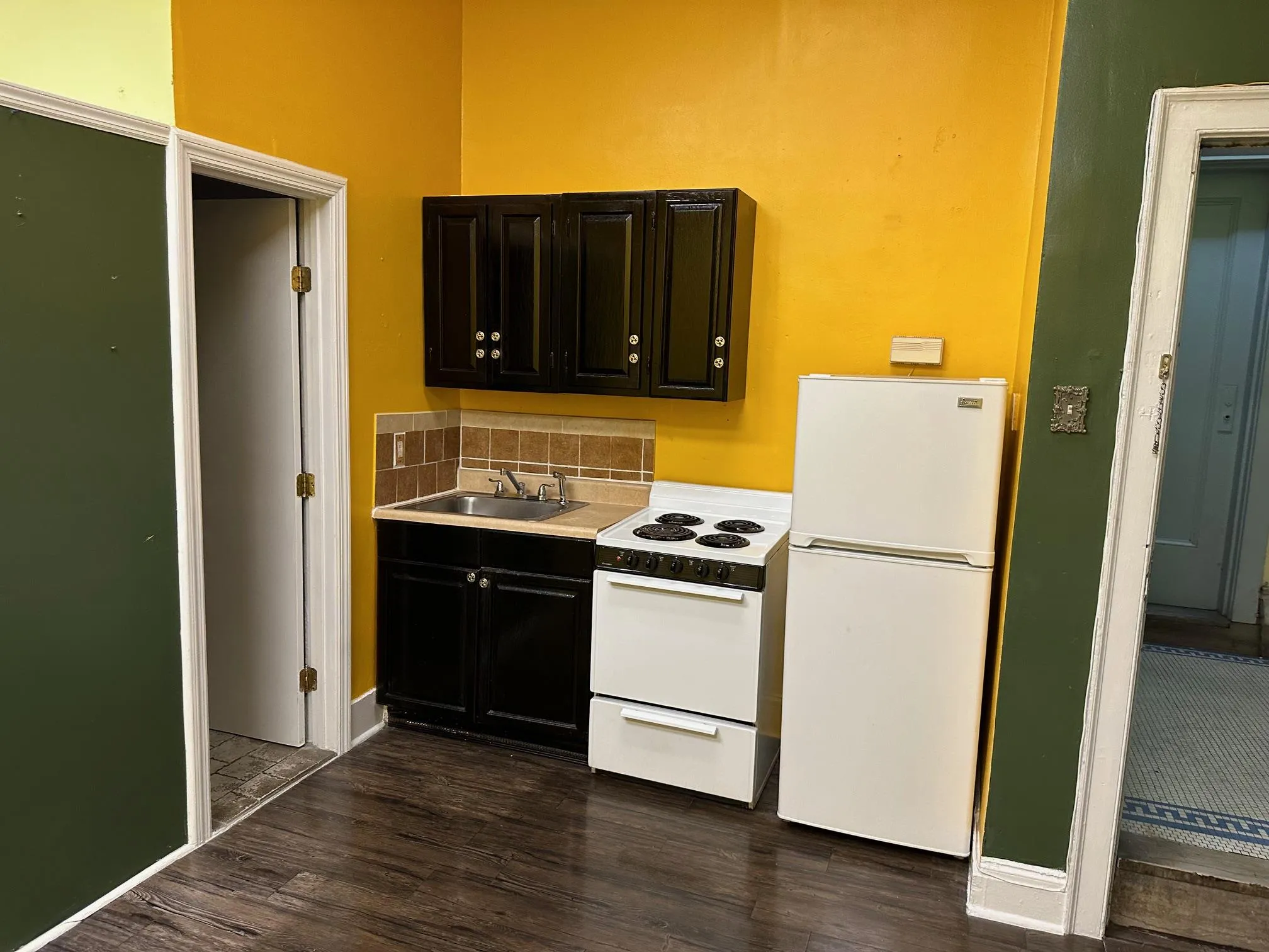 Kitchen featuring white appliances, backsplash, dark wood-type flooring, and sink Kitchen featuring white appliances, backsplash, dark wood-type flooring, and sink