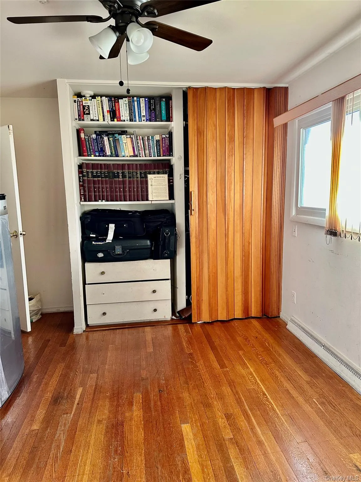 Unfurnished bedroom with hardwood / wood-style flooring, baseboard heating, and ceiling fan Unfurnished bedroom with hardwood / wood-style flooring, baseboard heating, and ceiling fan