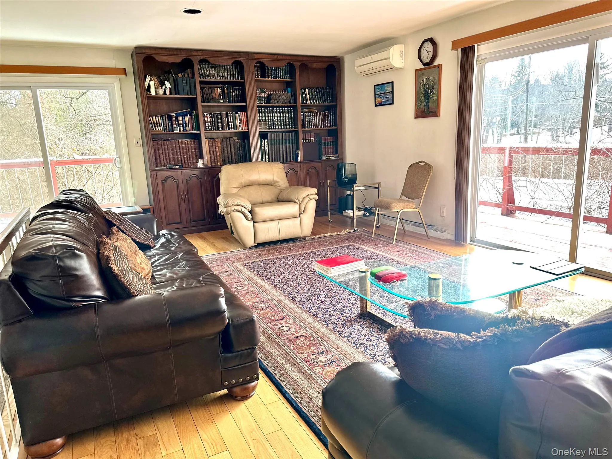 Living room with a wall unit AC, a wealth of natural light, and light hardwood / wood-style floors Living room with a wall unit AC, a wealth of natural light, and light hardwood / wood-style floors