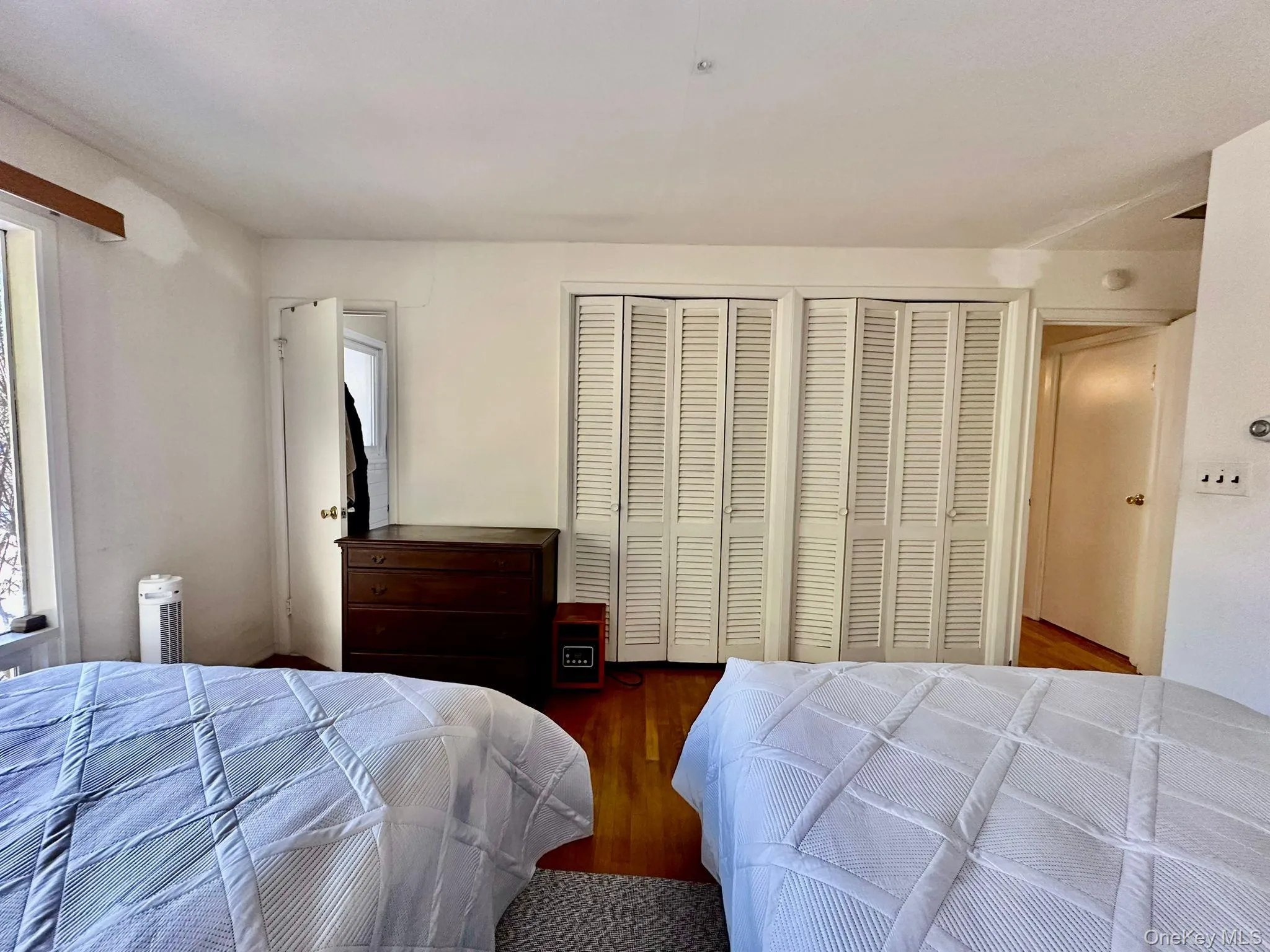 Bedroom featuring radiator, two closets, and hardwood / wood-style flooring Bedroom featuring radiator, two closets, and hardwood / wood-style flooring