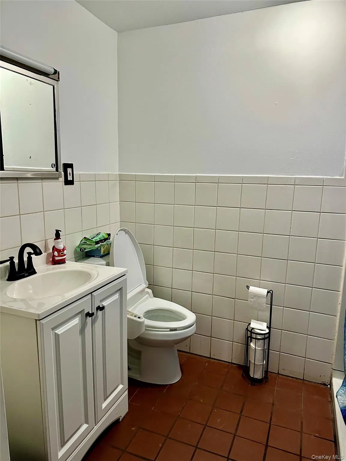 Bathroom with tile patterned floors, vanity, tile walls, and toilet Bathroom with tile patterned floors, vanity, tile walls, and toilet