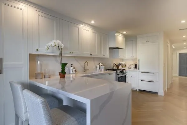Kitchen featuring white cabinets, kitchen peninsula, sink, and stainless steel stove Kitchen featuring white cabinets, kitchen peninsula, sink, and stainless steel stove