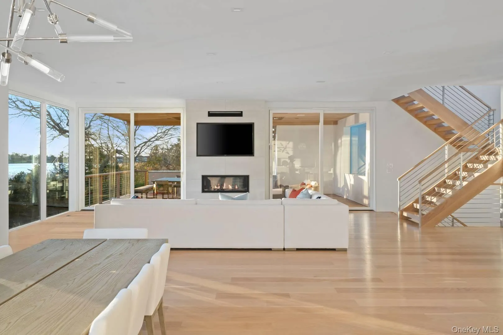 Living room with a large fireplace, light wood-type flooring, floor to ceiling windows, and an inviting chandelier Living room with a large fireplace, light wood-type flooring, floor to ceiling windows, and an inviting chandelier