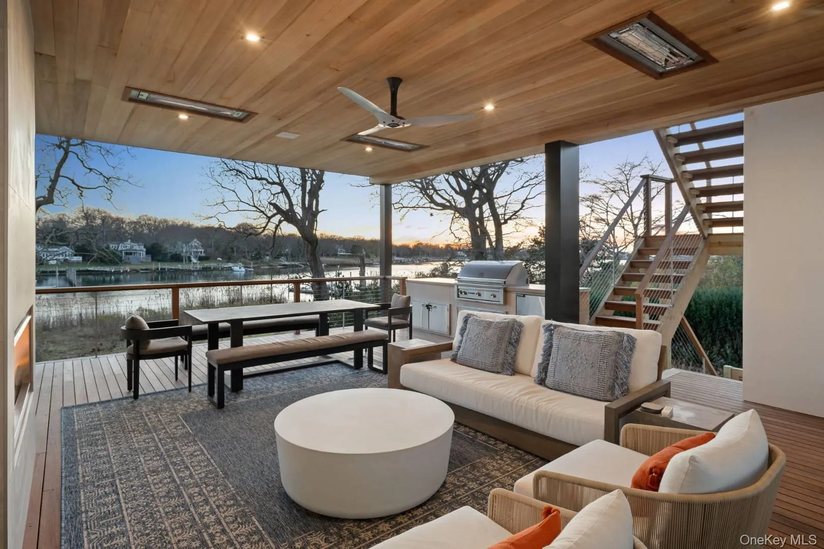 Patio terrace at dusk with outdoor lounge area, ceiling fan, exterior kitchen, grilling area, and a water view Patio terrace at dusk with outdoor lounge area, ceiling fan, exterior kitchen, grilling area, and a water view