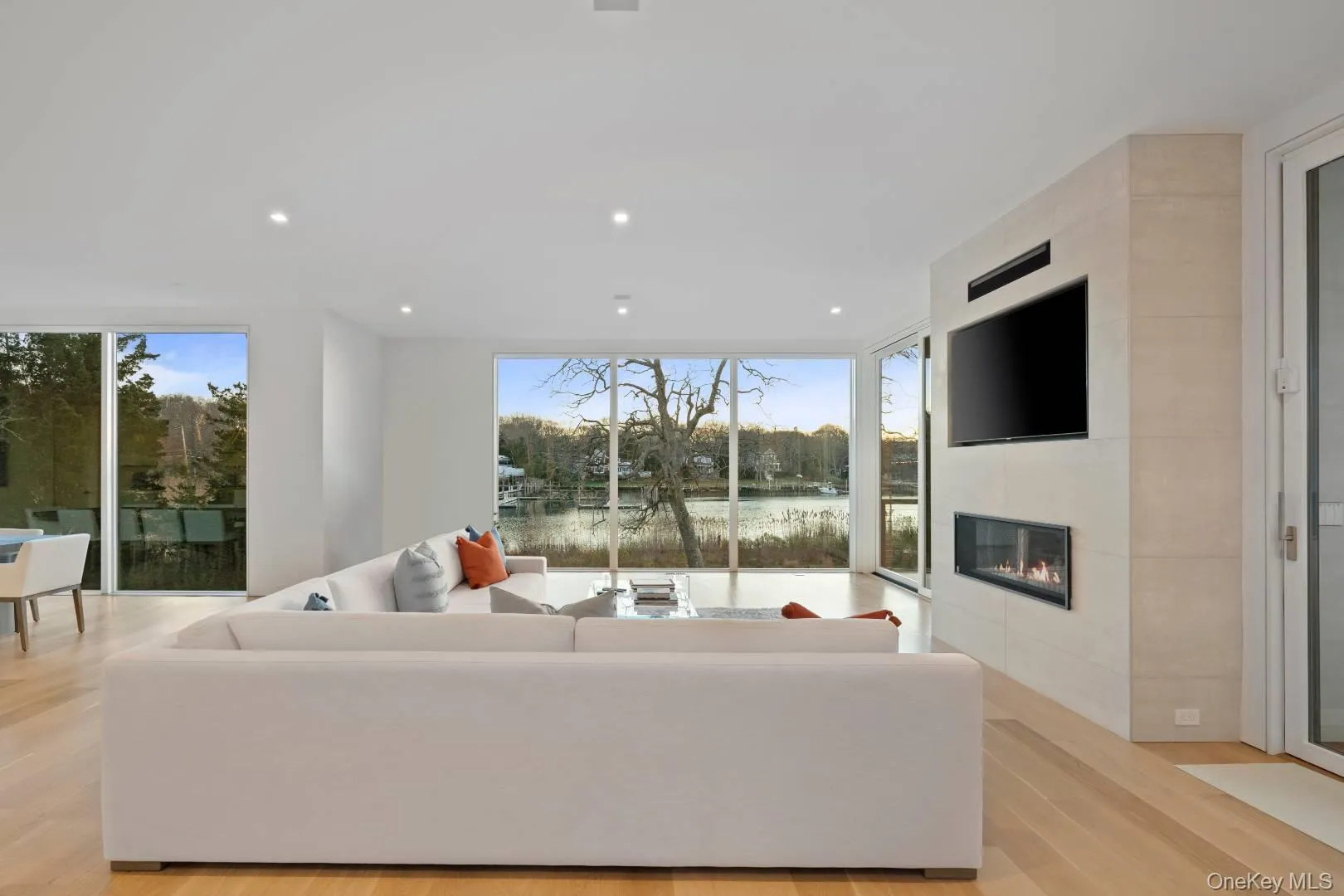 Living room featuring a tile fireplace, light hardwood / wood-style flooring, and a wealth of natural light Living room featuring a tile fireplace, light hardwood / wood-style flooring, and a wealth of natural light