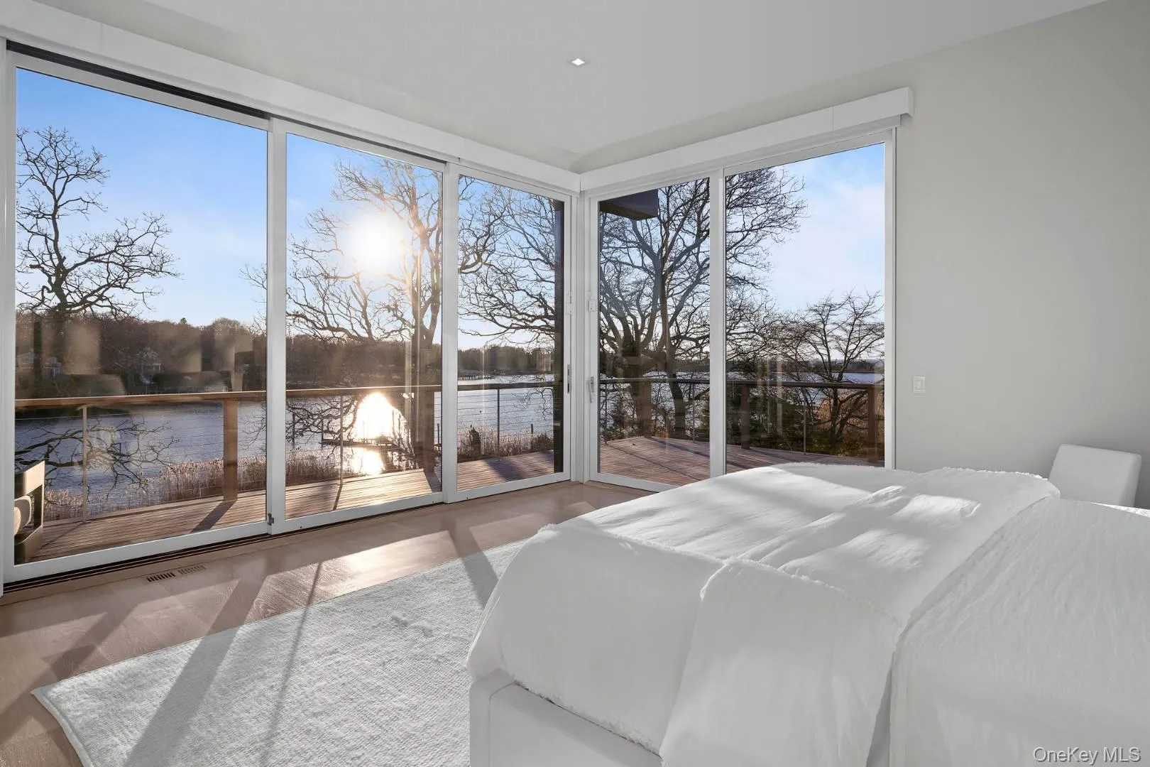 Bedroom featuring access to exterior, a water view, and wood-type flooring Bedroom featuring access to exterior, a water view, and wood-type flooring