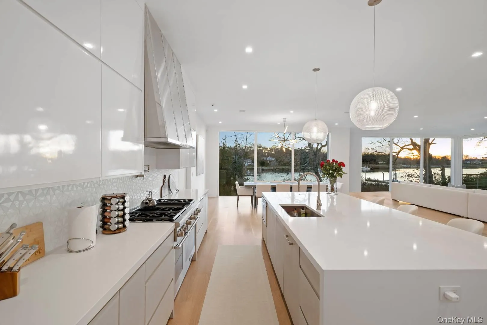 Kitchen featuring white cabinets, a healthy amount of sunlight, a spacious island, and sink Kitchen featuring white cabinets, a healthy amount of sunlight, a spacious island, and sink