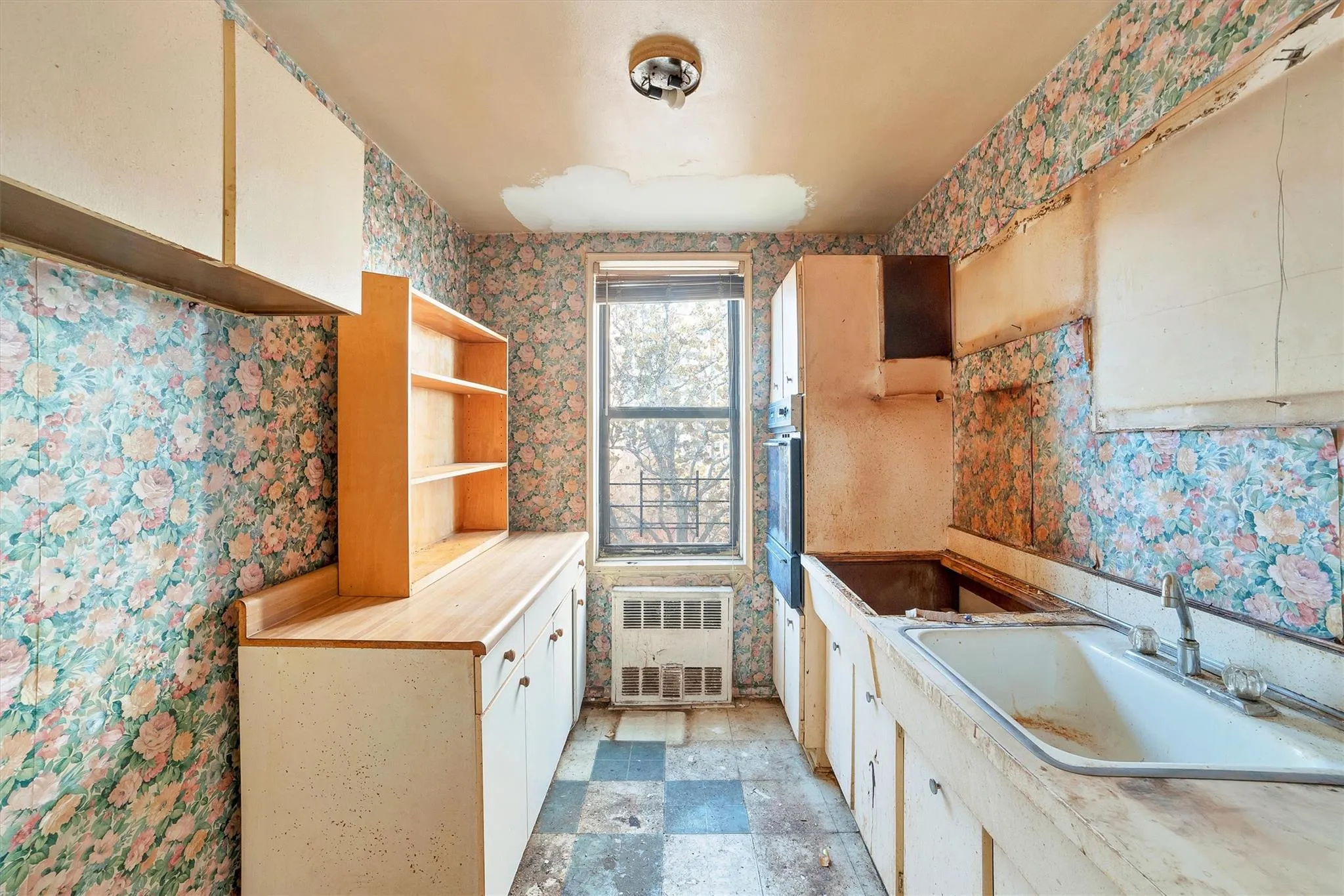 Kitchen featuring oven, radiator, sink, and white cabinetry Kitchen featuring oven, radiator, sink, and white cabinetry