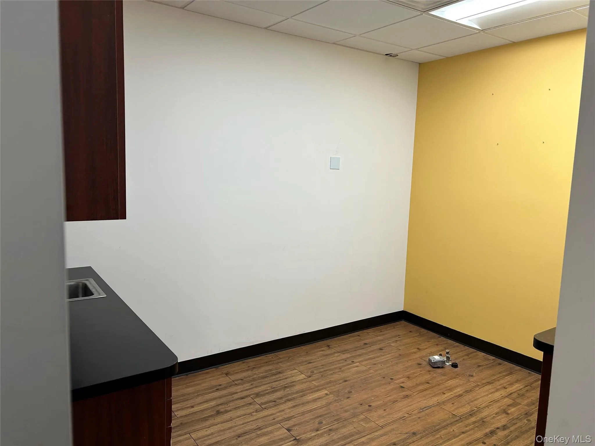 Unfurnished room with wood-type flooring and a drop ceiling Unfurnished room with wood-type flooring and a drop ceiling