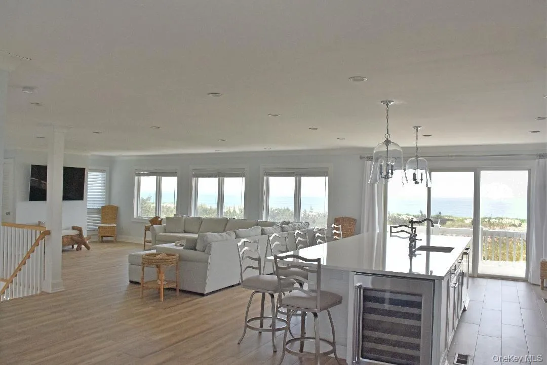 Kitchen featuring a center island with sink, a chandelier, light hardwood / wood-style floors, wine cooler, and hanging light fixtures Kitchen featuring a center island with sink, a chandelier, light hardwood / wood-style floors, wine cooler, and hanging light fixtures