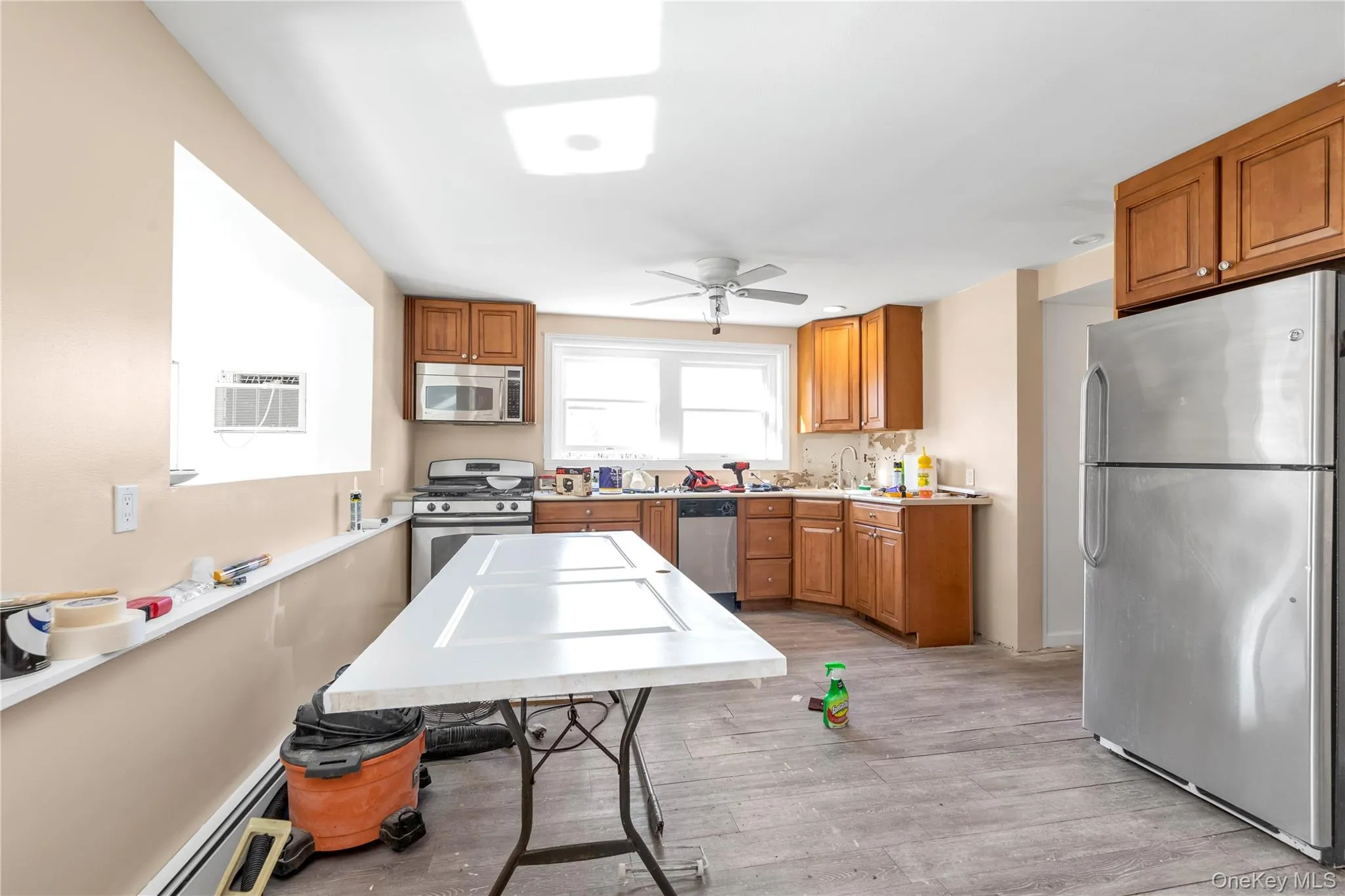 Kitchen with stainless steel appliances, light hardwood / wood-style flooring, ceiling fan, and a baseboard heating unit Kitchen with stainless steel appliances, light hardwood / wood-style flooring, ceiling fan, and a baseboard heating unit