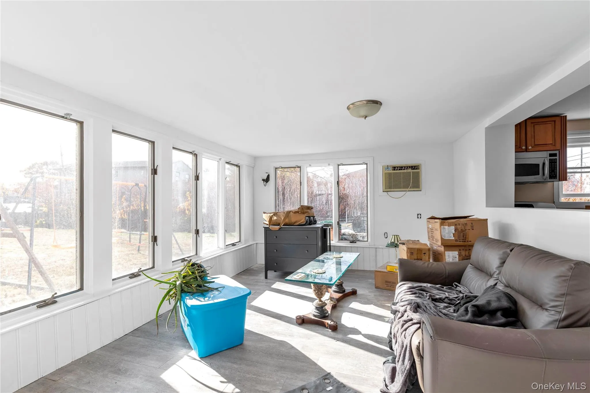 Living room with a healthy amount of sunlight, an AC wall unit, and light hardwood / wood-style flooring Living room with a healthy amount of sunlight, an AC wall unit, and light hardwood / wood-style flooring