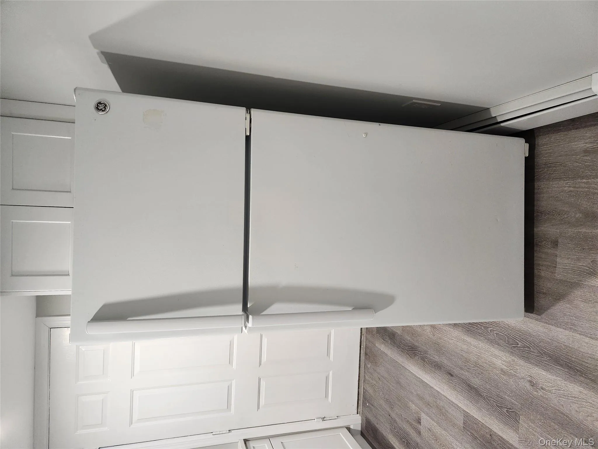 Kitchen with hardwood / wood-style floors, white refrigerator, and white cabinetry Kitchen with hardwood / wood-style floors, white refrigerator, and white cabinetry