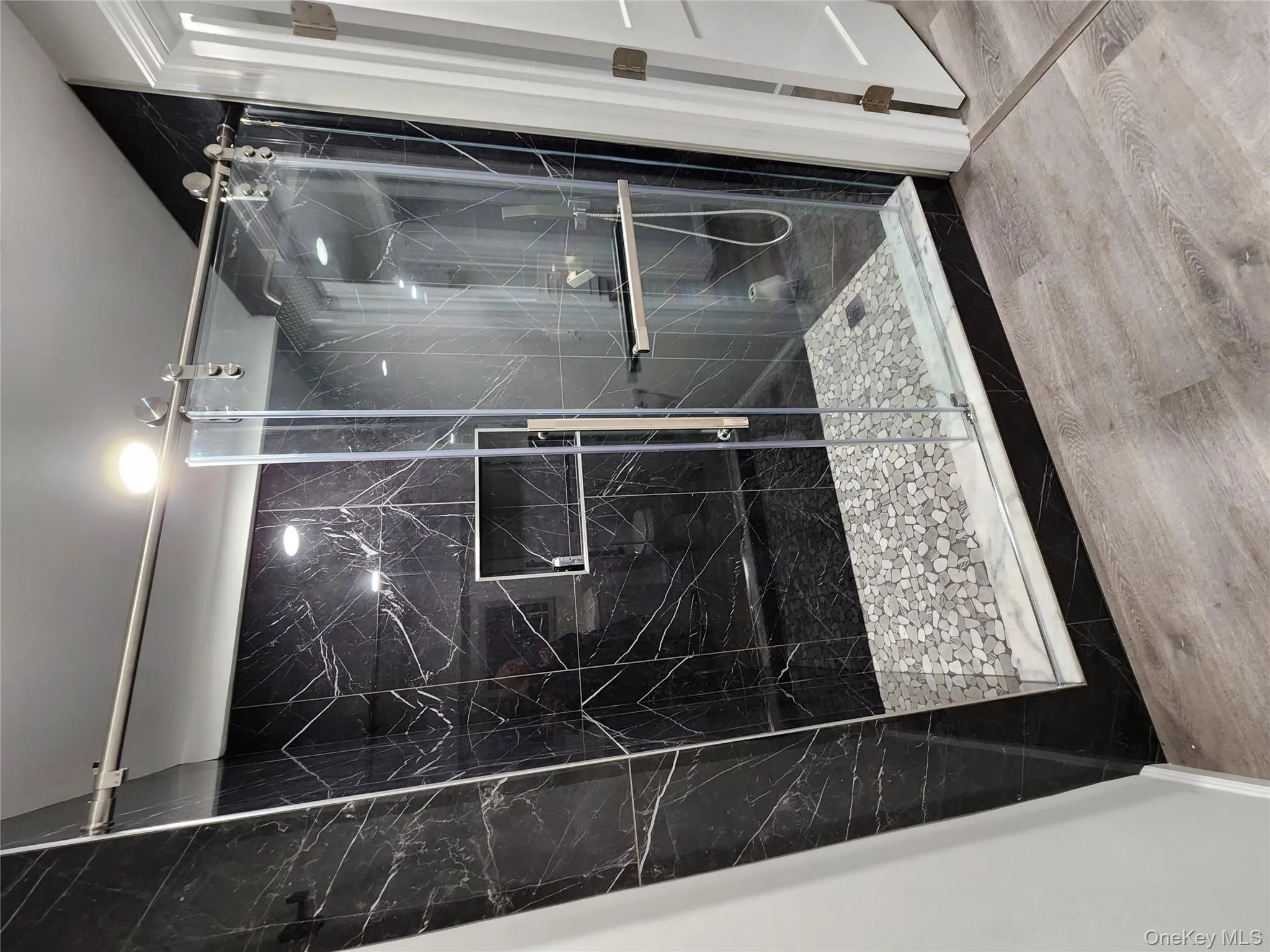 Bathroom featuring wood-type flooring and a designer marble shower with door Bathroom featuring wood-type flooring and a designer marble shower with door