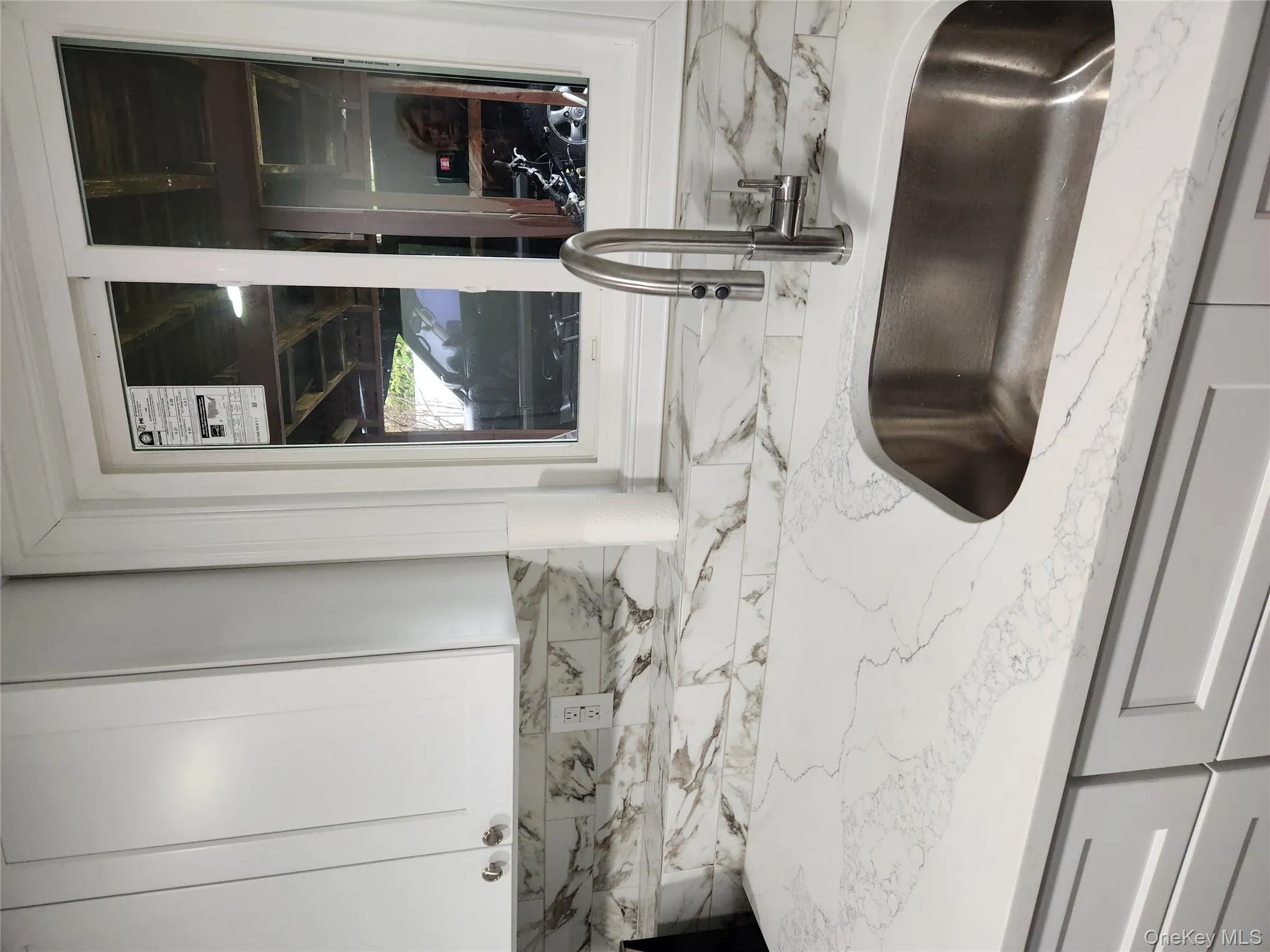 Interior details with white cabinets, backsplash, light stone countertops, and stainless steel sink Interior details with white cabinets, backsplash, light stone countertops, and stainless steel sink