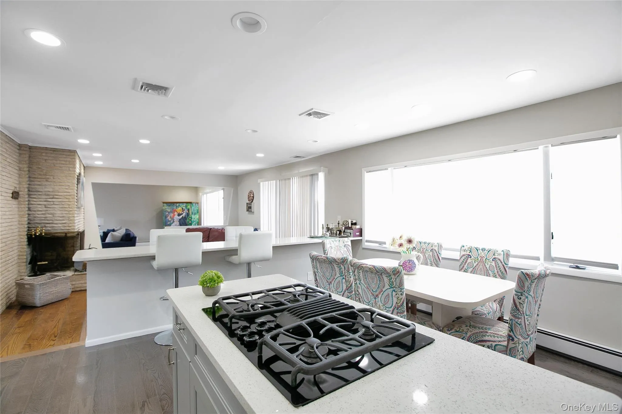 Kitchen with black gas cooktop, dark wood finished floors, recessed lighting, white cabinetry, and light stone countertops Kitchen with black gas cooktop, dark wood finished floors, recessed lighting, white cabinetry, and light stone countertops