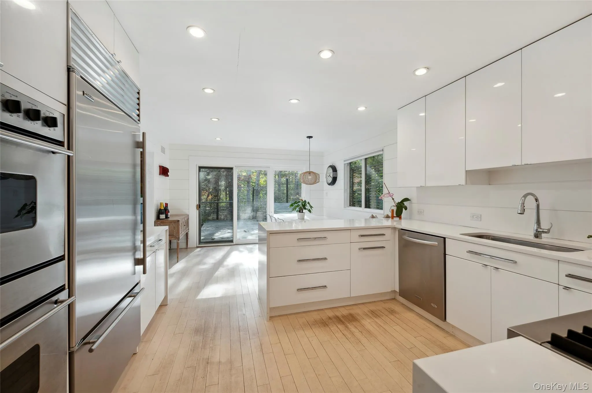 Kitchen featuring sink, kitchen peninsula, pendant lighting, white cabinets, and appliances with stainless steel finishes Kitchen featuring sink, kitchen peninsula, pendant lighting, white cabinets, and appliances with stainless steel finishes