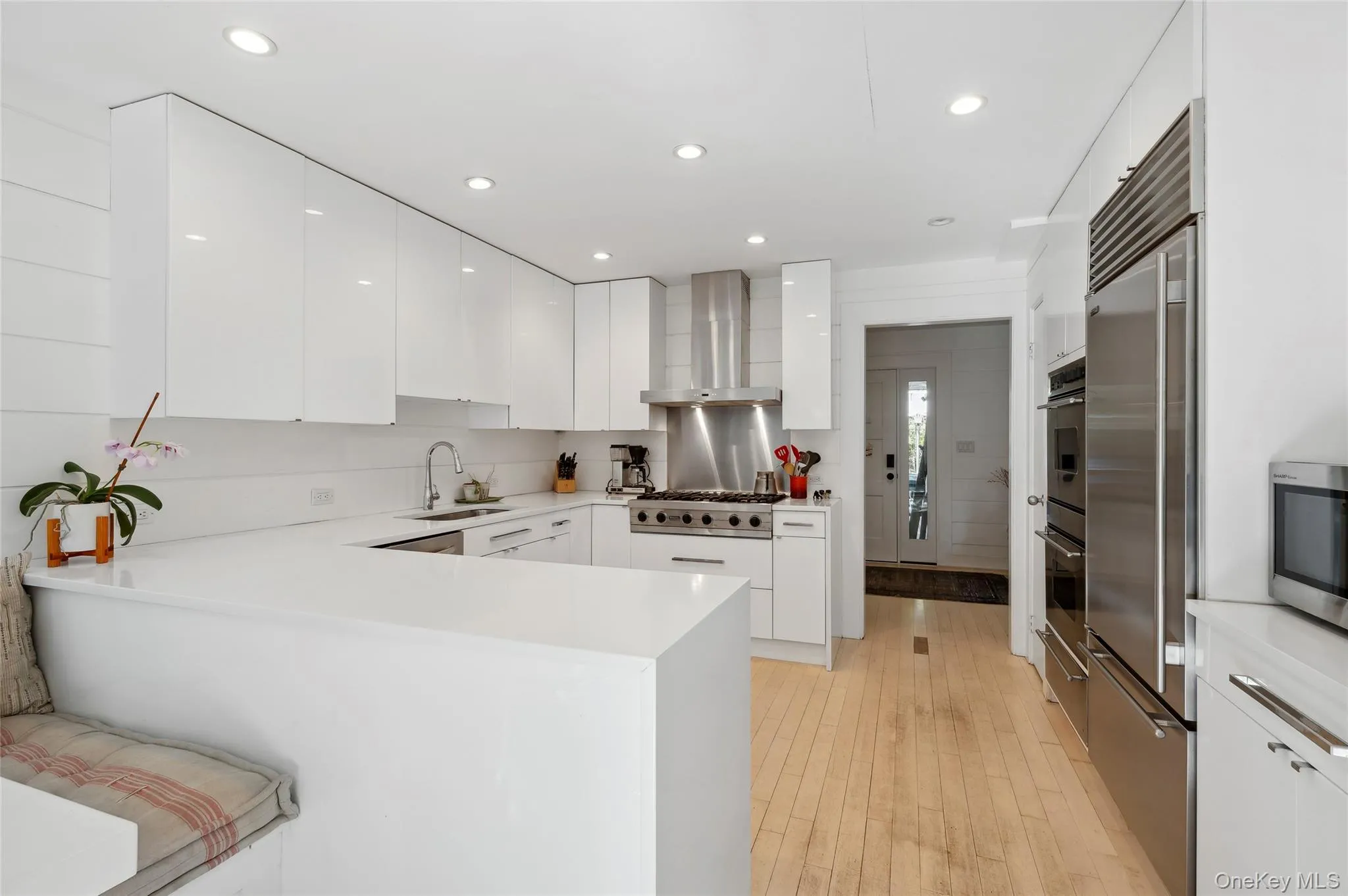 Kitchen with white cabinets, wall chimney exhaust hood, kitchen peninsula, and sink Kitchen with white cabinets, wall chimney exhaust hood, kitchen peninsula, and sink