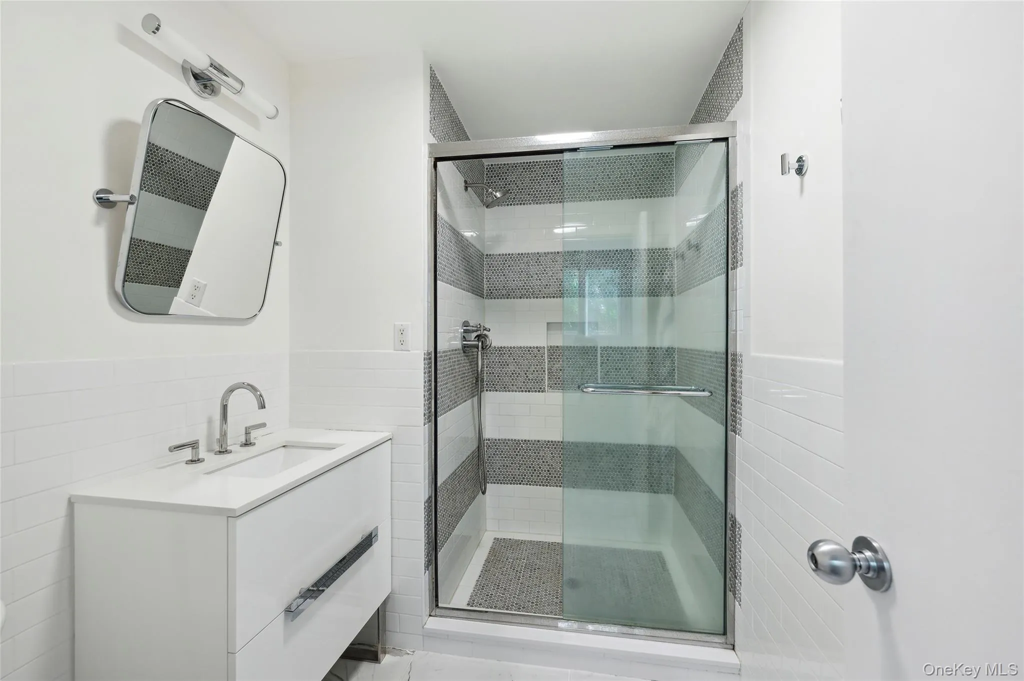Bathroom with vanity, a shower with door, and tile walls Bathroom with vanity, a shower with door, and tile walls