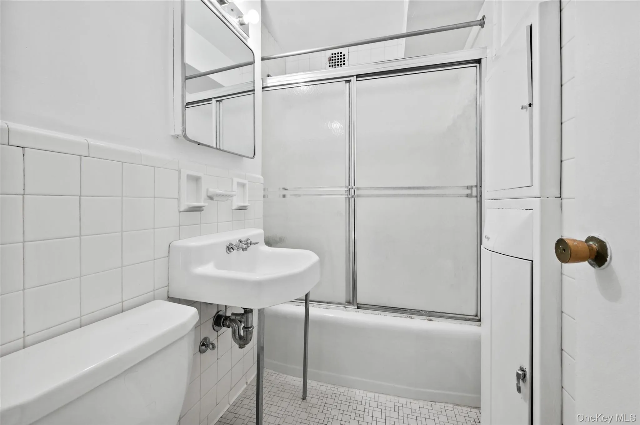 Full bathroom with tile patterned flooring, toilet, shower / bath combination with glass door, and tile walls Full bathroom with tile patterned flooring, toilet, shower / bath combination with glass door, and tile walls
