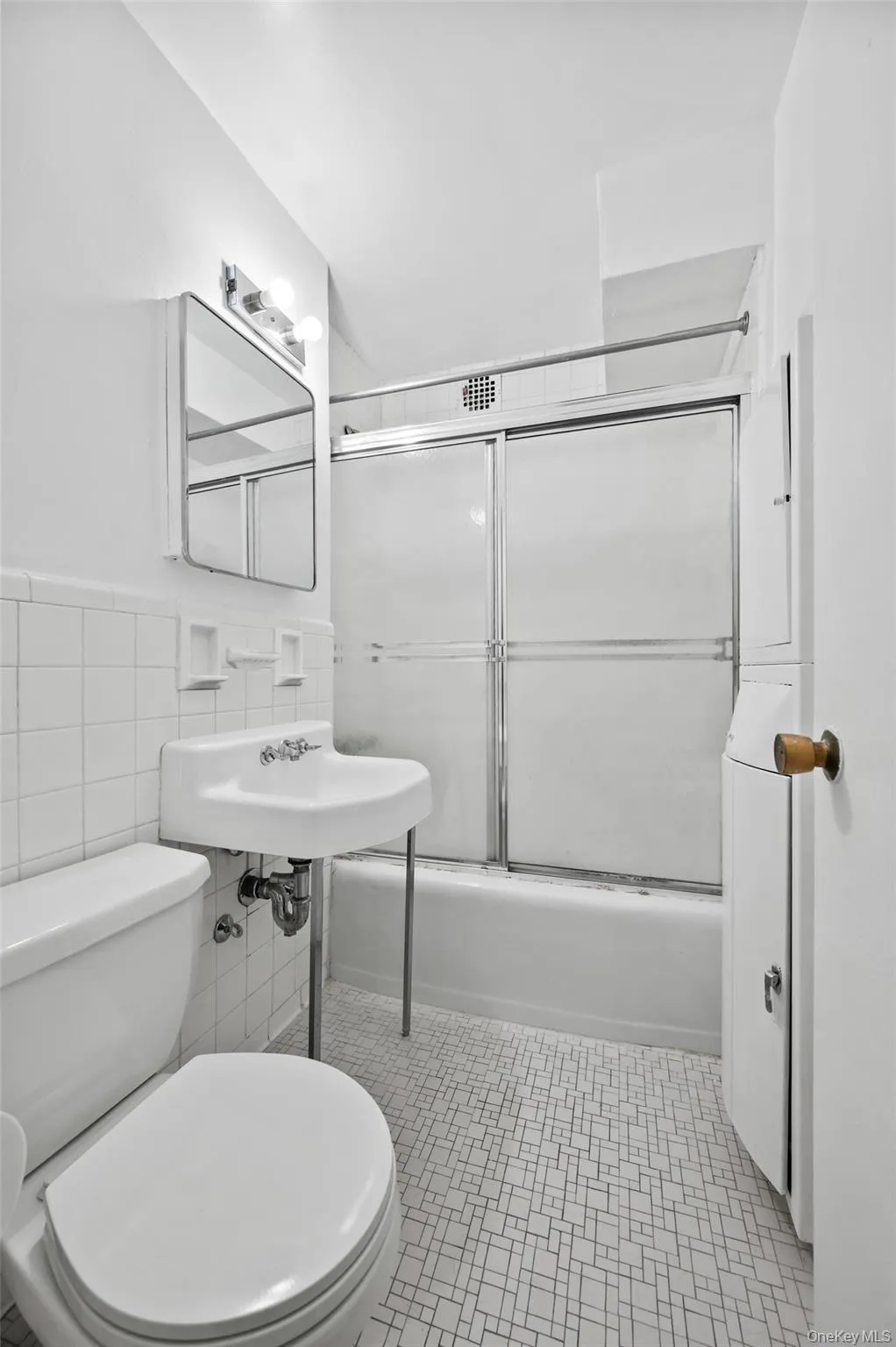 Bathroom featuring toilet, combined bath / shower with glass door, and tile walls Bathroom featuring toilet, combined bath / shower with glass door, and tile walls