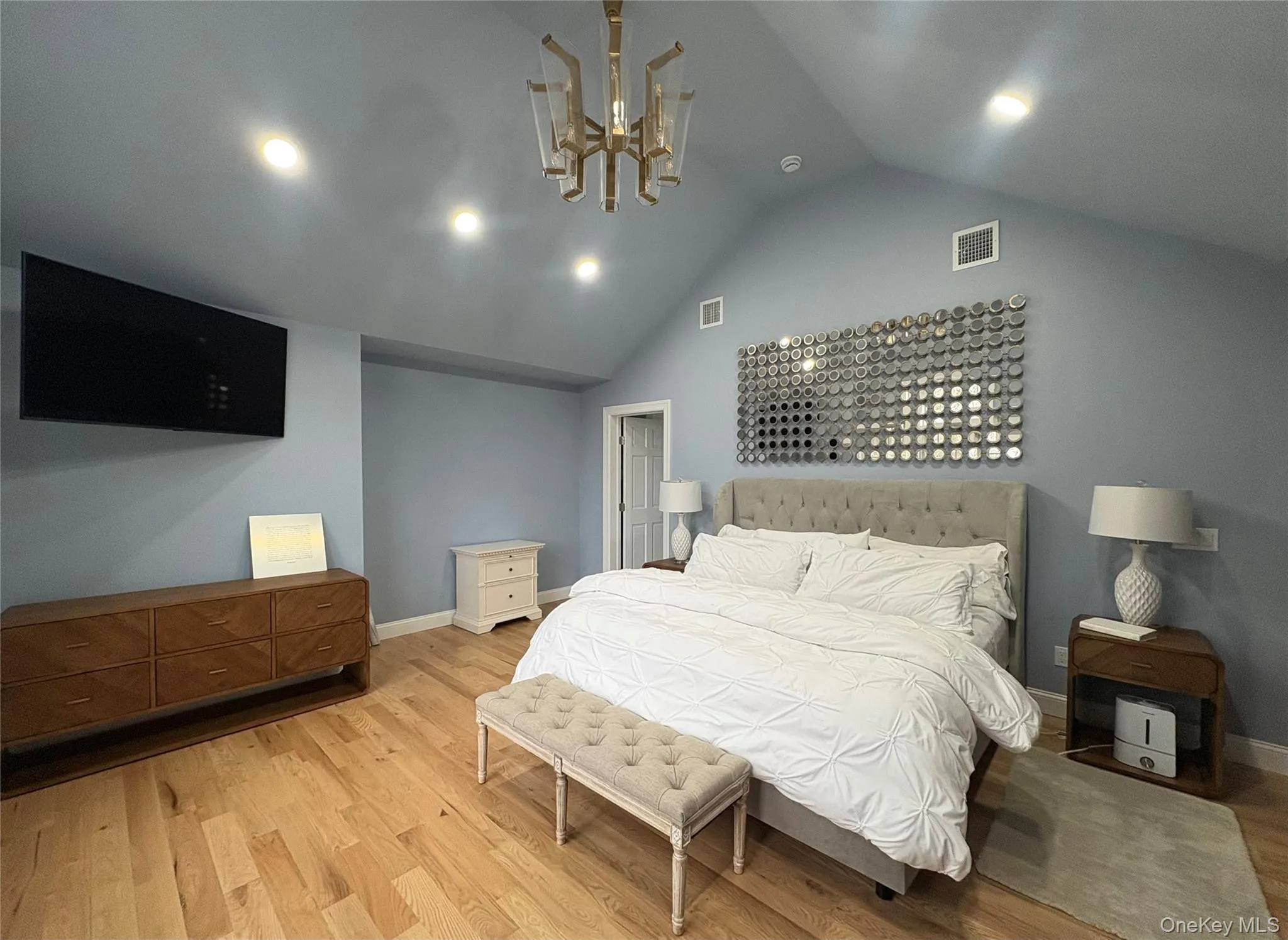 Bedroom with an inviting chandelier, vaulted ceiling, and light hardwood / wood-style floors Bedroom with an inviting chandelier, vaulted ceiling, and light hardwood / wood-style floors
