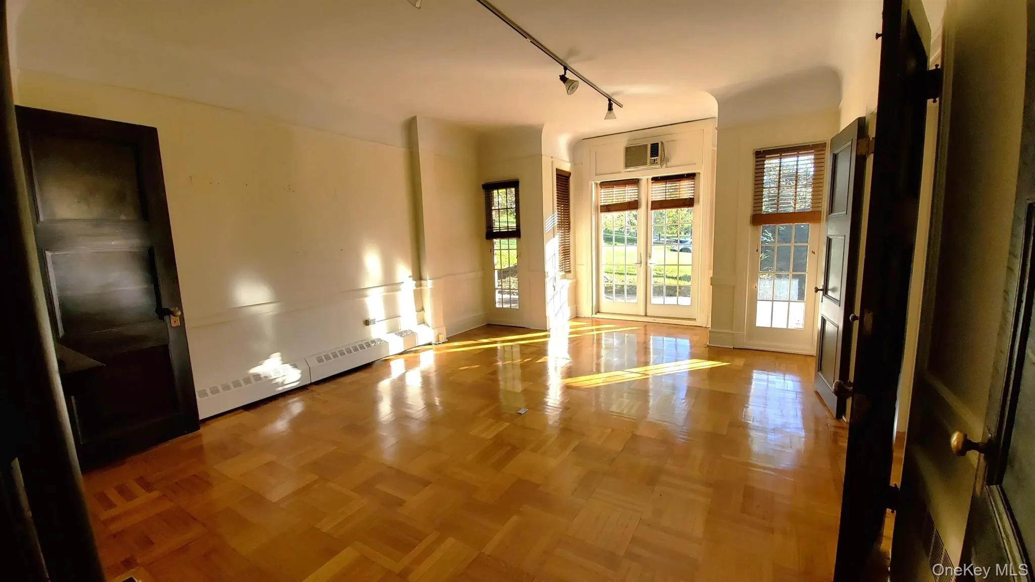 Large room with light parquet flooring and track lighting. Large room with light parquet flooring and track lighting.