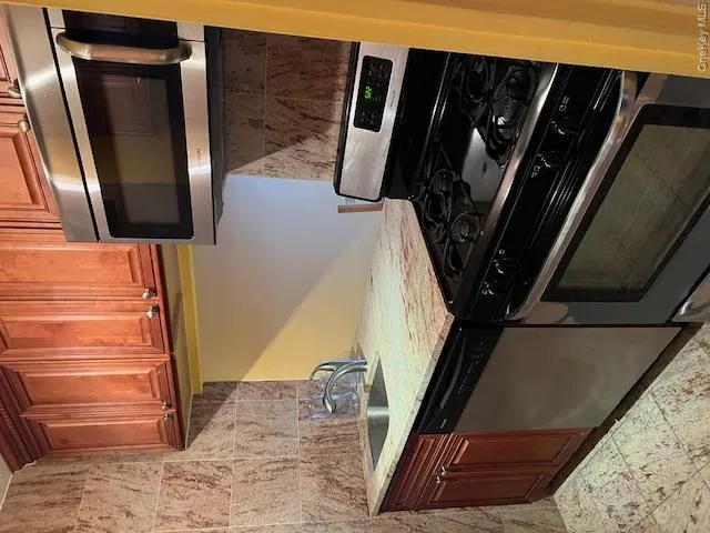Kitchen with dishwasher, light stone countertops, range, and sink Kitchen with dishwasher, light stone countertops, range, and sink