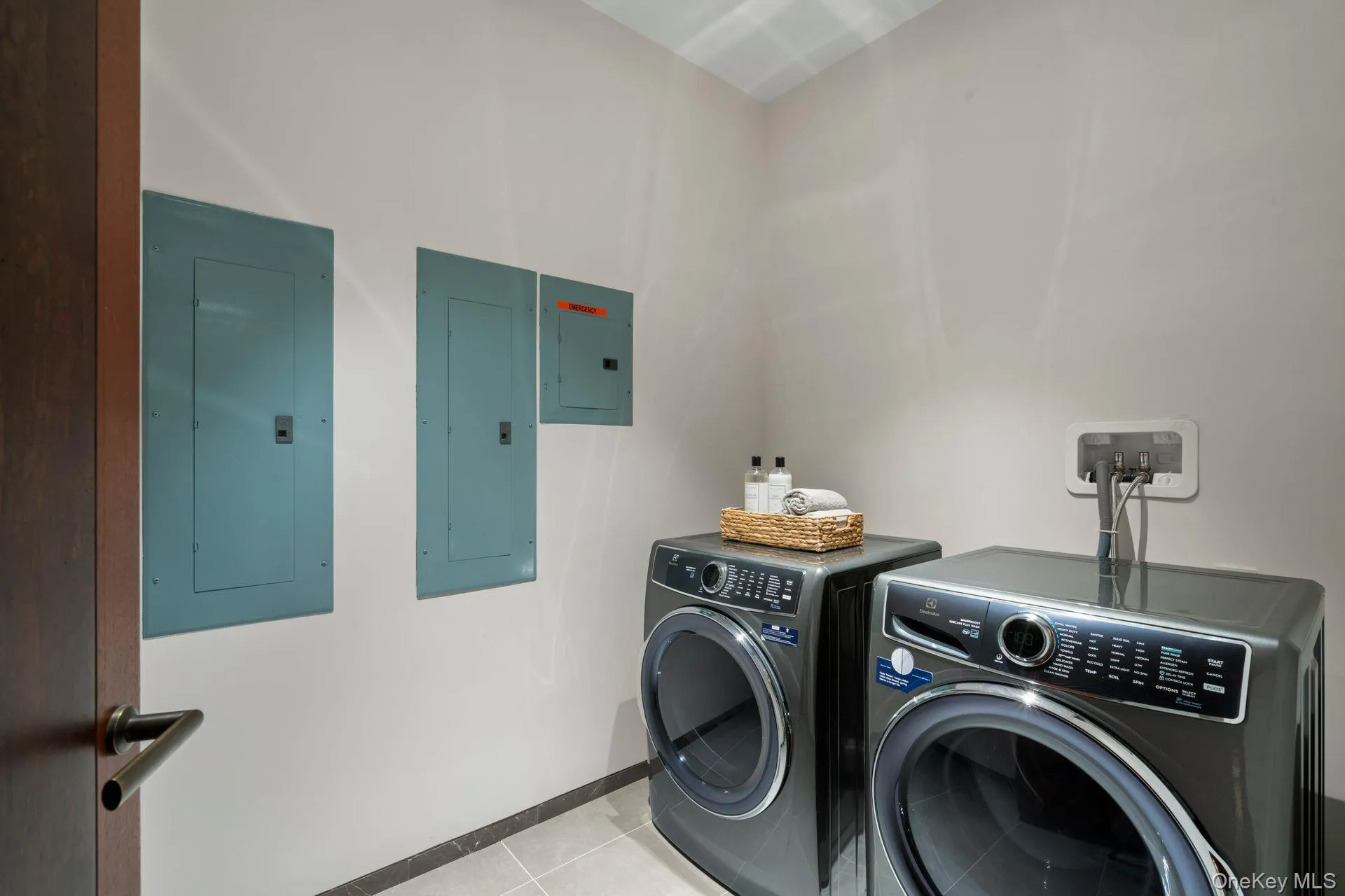 Washroom featuring laundry area, electric panel, light tile patterned floors, and independent washer and dryer Washroom featuring laundry area, electric panel, light tile patterned floors, and independent washer and dryer