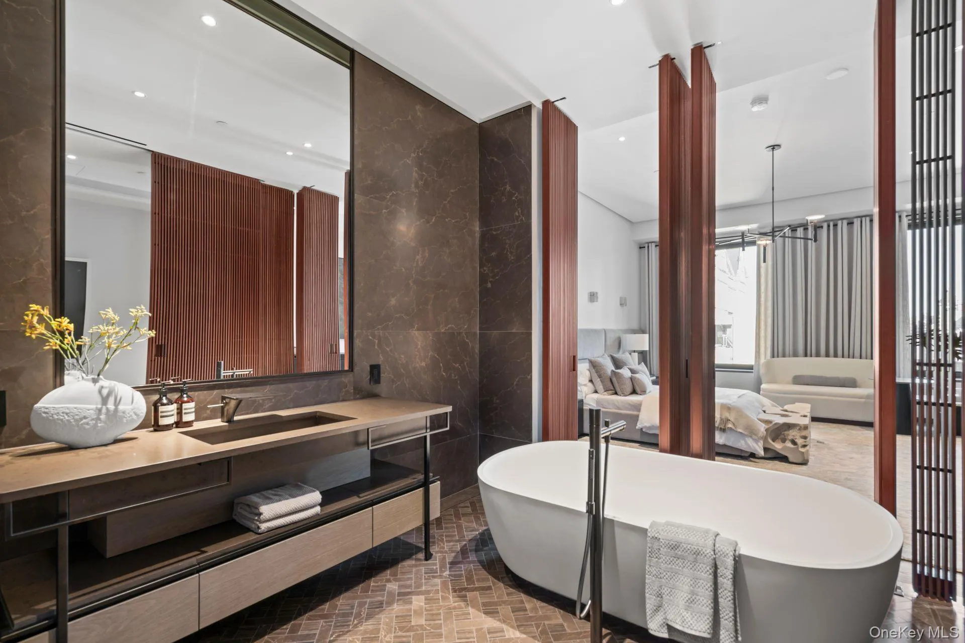 Full bathroom featuring a chandelier, brick floor, a freestanding tub, vanity, and tile walls Full bathroom featuring a chandelier, brick floor, a freestanding tub, vanity, and tile walls