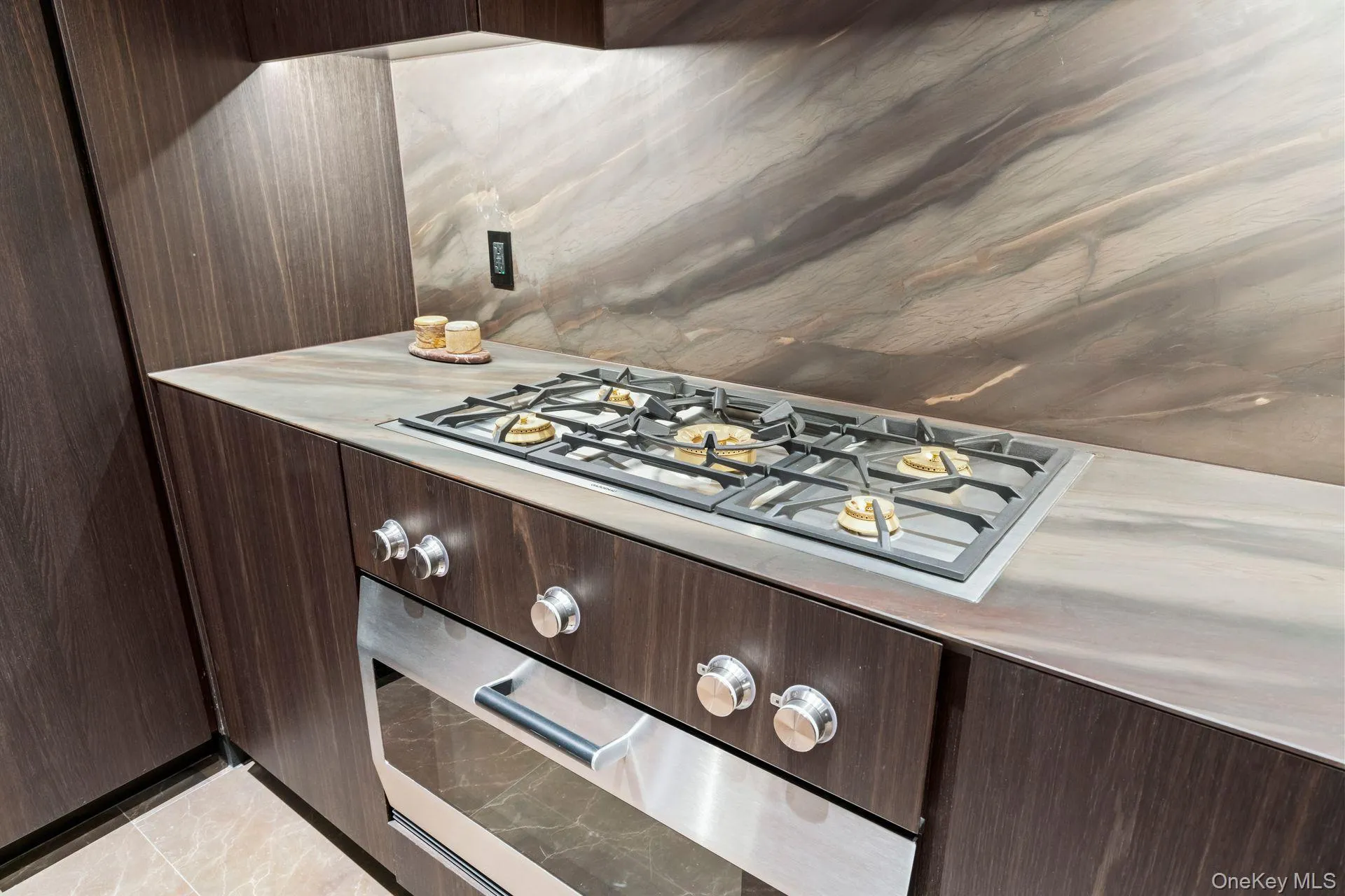 Kitchen with light countertops, cooktop, and dark brown cabinetry Kitchen with light countertops, cooktop, and dark brown cabinetry