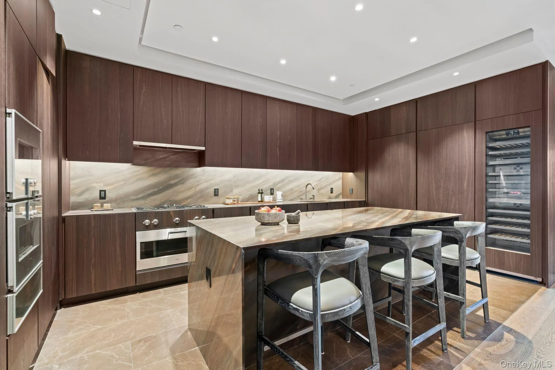 Kitchen with a breakfast bar area, light countertops, appliances with stainless steel finishes, a warming drawer, and modern cabinets Kitchen with a breakfast bar area, light countertops, appliances with stainless steel finishes, a warming drawer, and modern cabinets
