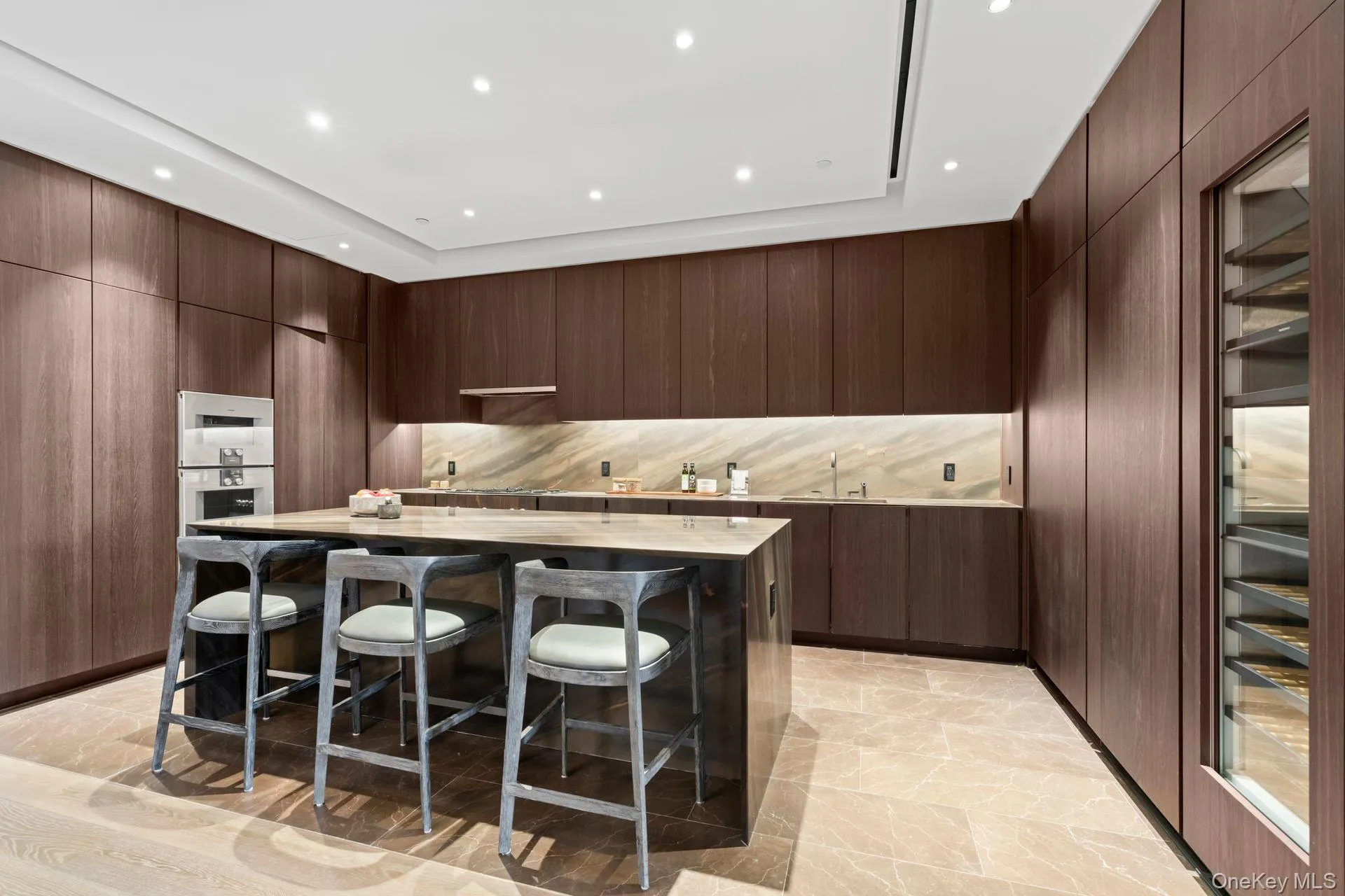 Kitchen with modern cabinets, a breakfast bar area, a center island, light countertops, and stainless steel double oven Kitchen with modern cabinets, a breakfast bar area, a center island, light countertops, and stainless steel double oven