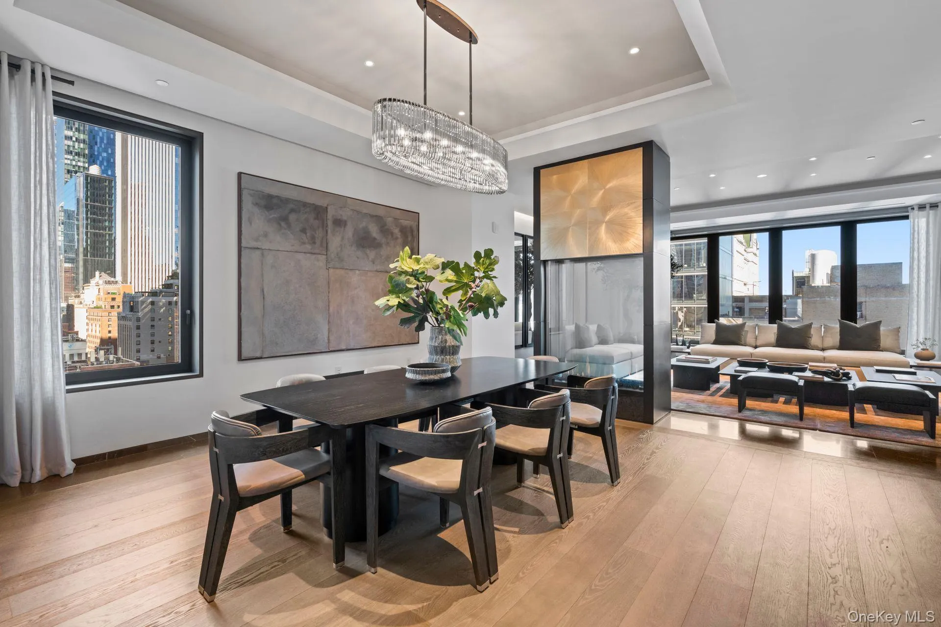 Dining room featuring light wood finished floors, a tray ceiling, a view of city, and a healthy amount of sunlight Dining room featuring light wood finished floors, a tray ceiling, a view of city, and a healthy amount of sunlight